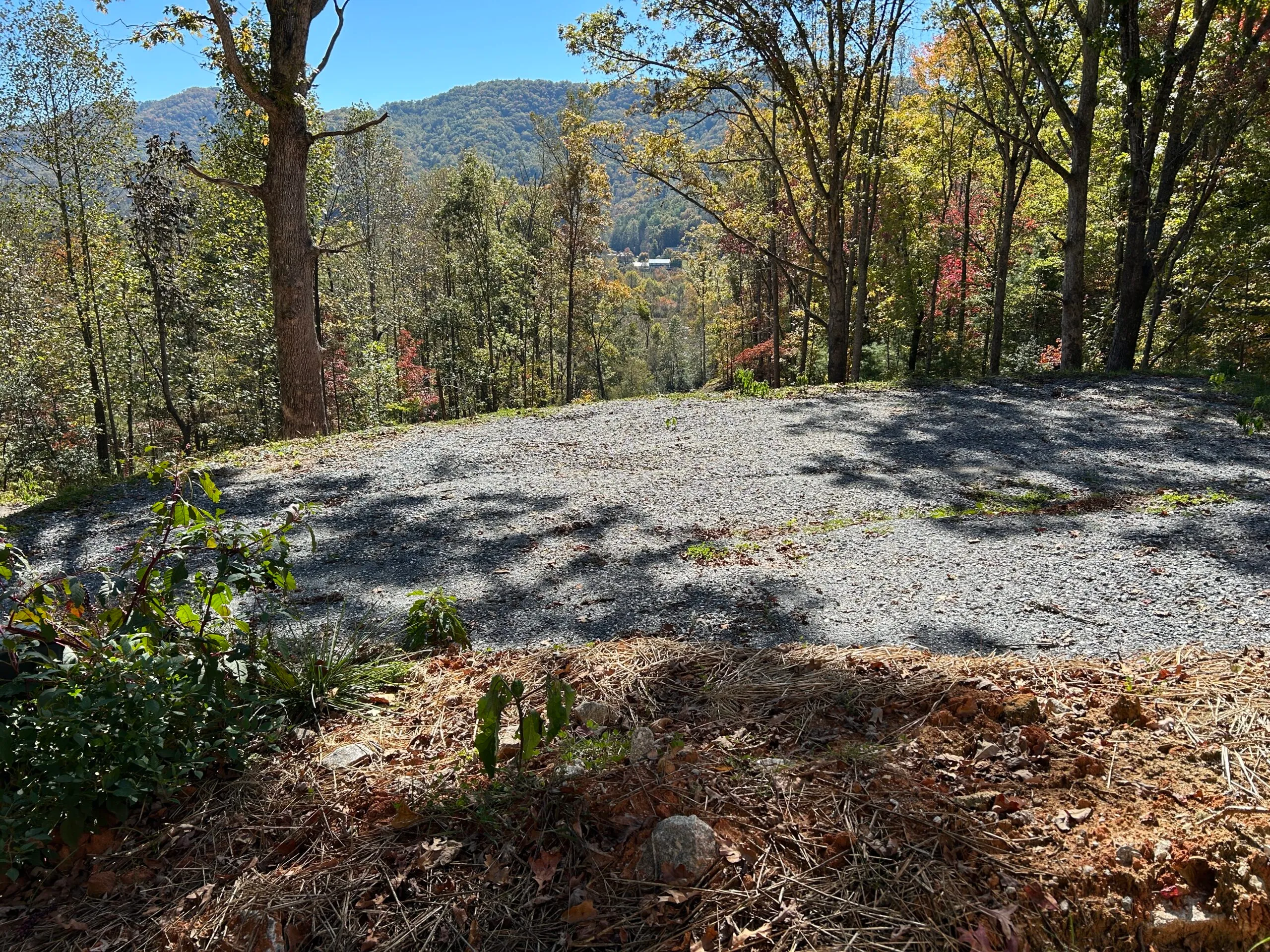 Cleared gravel area surrounded by colorful trees and mountains